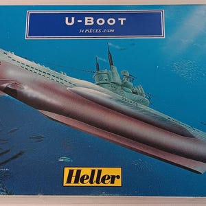 Puede incluir: Una caja de maqueta para un submarino U-Boot. La caja presenta un fondo azul con un submarino blanco y el texto "U-BOAT 14 PIECES - 1/100" y "HELLER".