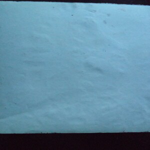 May include: A plain white sheet of paper with a slightly textured surface. The paper has a few small dark spots.