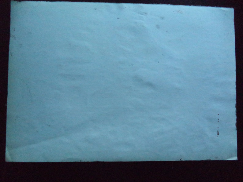 May include: A plain white sheet of paper with a slightly textured surface. The paper has a few small dark spots.