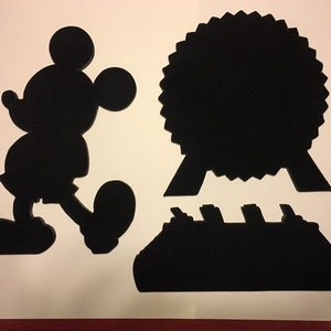 May include: Black silhouette cutouts of Mickey Mouse, a cruise ship, and a Ferris wheel. The cutouts are on a white background.