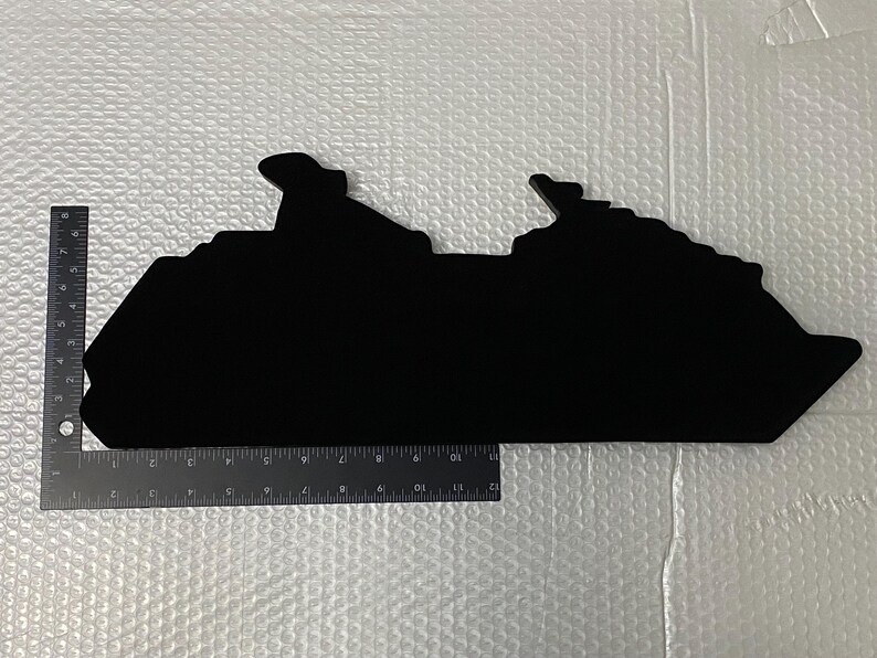 May include: Black silhouette of a cruise ship, cut out of a material like wood or cardboard. The silhouette is about 12 inches long.