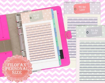 May include: A pink Filofax personal size binder with a white to-do list page with a heart pattern. The page has the text "To Do List" on a tag. There are also two additional to-do list pages with a heart pattern in light purple and light green.