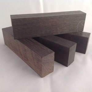 May include: Four dark brown wooden blocks stacked on top of each other. The blocks are rectangular and have a smooth, polished surface.