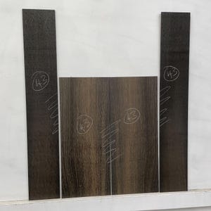 May include: Four pieces of wood, two long and two square, with a dark brown grain pattern. Each piece has the number "43" written in a circle with white marker. The wood has a natural, textured appearance.