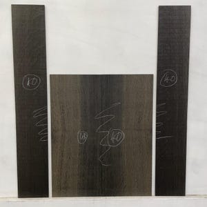 May include: A collection of dark wood pieces, likely for woodworking. The image shows three rectangular pieces and one square piece of wood. The wood grain is visible, and the pieces have handwritten markings, including the number "40" in circles.