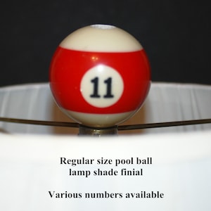 May include: A red and white pool ball with the number 11 on it. The ball is used as a lamp shade finial. Regular size pool ball lamp shade finial. Various numbers available.