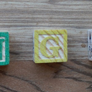 Puede incluir: Bloques de madera que deletrean la palabra "ANGEL" en rojo, verde, amarillo, rojo y azul.