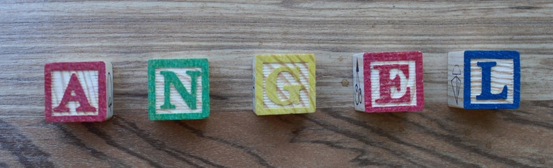 Puede incluir: Bloques de madera que deletrean la palabra "ANGEL" en rojo, verde, amarillo, rojo y azul.