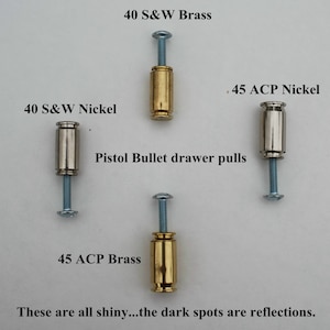 May include: Four different styles of pistol bullet drawer pulls. The pulls are made of brass and nickel. The text on the image reads "40 S&W Nickel", "40 S&W Brass", "45 ACP Nickel", "45 ACP Brass", "Pistol Bullet drawer pulls", and "These are all shiny...the dark spots are reflections."
