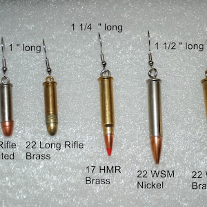 May include: Five pairs of bullet-shaped earrings in different sizes and finishes. The earrings are 1 inch, 1 1/4 inches, and 1 1/2 inches long. The bullets are made of nickel-plated brass and brass.