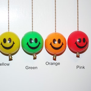 May include: Four smiley face light pull chains in yellow, green, orange, and pink.