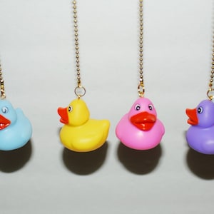 May include: Four rubber ducky pull chains in blue, yellow, pink, and purple. The ducks are hanging from gold chains.