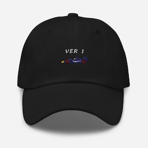 May include: Black baseball cap with the text "VER 1" above a small embroidered race car design in blue, yellow, and red. The cap has a curved brim and a structured fit.