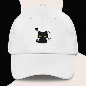 Puede incluir: Gorra de béisbol blanca con un gato negro bordado con ojos amarillos y una expresión enfadada. El gato tiene una burbuja de pensamiento y acentos de relámpagos. Gorra casual y ajustable.