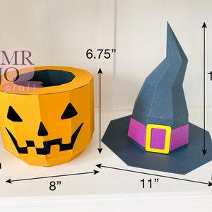 May include: A Halloween-themed papercraft set featuring a jack-o'-lantern bucket (8" x 8" x 6.75") and a witch's hat (11" x 11" x 11.5"). The jack-o'-lantern is orange with black cut-out features. The witch's hat is dark gray with a purple band and yellow buckle.