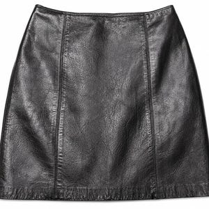 May include: A black leather skirt with a smooth, slightly textured finish. The garment features a high-waisted design with vertical seam detailing running down the front panels, creating a structured, A-line silhouette with a straight hemline.