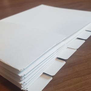 Puede incluir: Una pila de papel blanco con pesta&ntilde;as a lo largo del borde. Las pesta&ntilde;as est&aacute;n espaciadas uniformemente y son todas del mismo tama&ntilde;o.