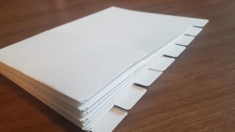 Puede incluir: Una pila de papel blanco con pesta&ntilde;as a lo largo del borde. Las pesta&ntilde;as est&aacute;n espaciadas uniformemente y son todas del mismo tama&ntilde;o.