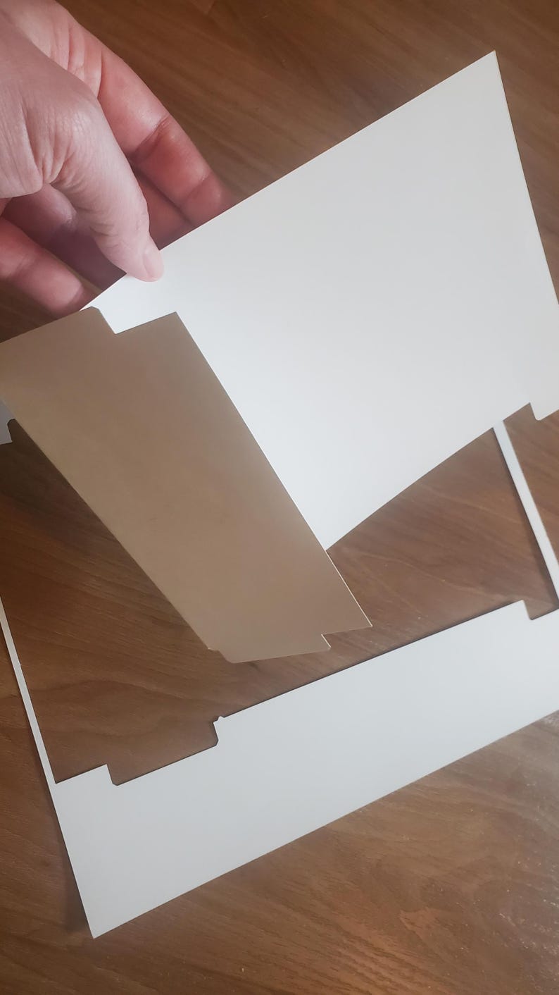 Puede incluir: Una tarjeta blanca con un dise&ntilde;o recortado, que muestra una tarjeta blanca m&aacute;s peque&ntilde;a con un dise&ntilde;o recortado. La tarjeta m&aacute;s peque&ntilde;a se levanta para revelar la tarjeta m&aacute;s grande.