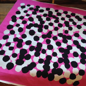 May include: Pink fabric with a repeating pattern of black and white circles. The circles are of varying sizes and are arranged in a random pattern.