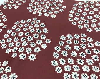 Puede incluir: Primer plano de una tela con un patrón repetitivo de círculos blancos con puntos negros sobre un fondo marrón.