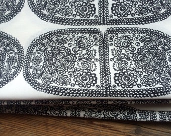 May include: Black and white fabric with a repeating pattern of paisley shapes. The fabric is folded in thirds.