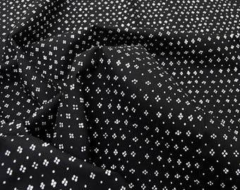 May include: Black fabric with a white, repeating pattern of small, four-leaf clover shapes.