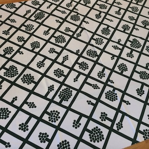May include: White fabric with a repeating pattern of dark green stylized trees. The trees are made up of small circles and are arranged in a grid pattern.