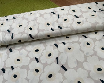 Puede incluir: Tela con estampado floral. Grandes flores blancas con centros y tallos negros sobre un fondo gris claro. La tela está doblada, mostrando el patrón en dos capas.