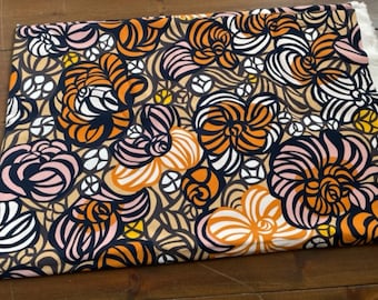 May include: A fabric with a floral pattern in shades of orange, pink, white, and black on a beige background.