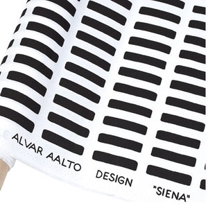 May include: Black and white fabric with a repeating pattern of horizontal rectangles. The fabric has the text "Alvar Aalto Design "Siena"" printed on it.