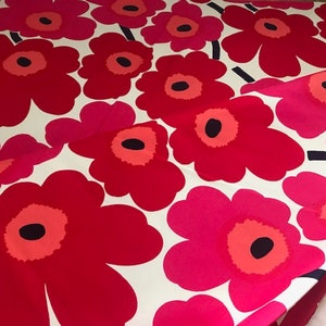 Può includere: Tessuto floreale rosso e rosa su sfondo bianco. Il tessuto presenta un motivo ripetitivo di grandi fiori stilizzati.