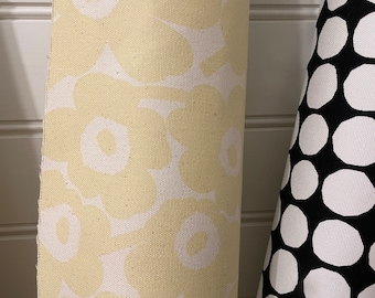 May include: A close-up of a yellow and white fabric with a floral pattern. The fabric is rolled up and the pattern is visible on the front and back of the roll.