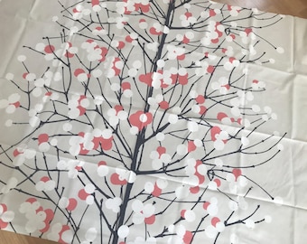 Puede incluir: Una tela blanca con un diseño de árbol blanco y negro con bayas rojas. El árbol está estilizado y tiene un diseño simple.