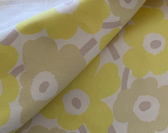 May include: Close-up of a fabric with a repeating floral pattern. The flowers are in shades of yellow and light green, with a white center and a light brown stem. The background is off-white.