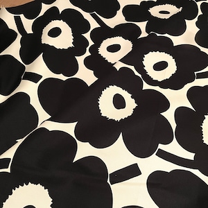 Könnte beinhalten: Schwarz-weißes Stoffmuster mit einem sich wiederholenden Muster aus großen, stilisierten Blumen. Die Blumen haben einen weißen Mittelpunkt und schwarze Blütenblätter.