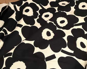 May include: Black and white fabric with a repeating pattern of large, stylized flowers. The flowers have a white center and black petals.