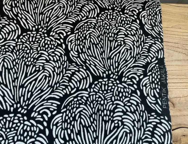 May include: Black and white fabric with a repeating pattern of abstract shapes. The fabric has the text "PENTIK JAKALA" printed on the side.
