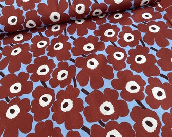 May include: A blue fabric with a repeating pattern of large, brown flowers with white centers. The flowers are stylized and have five petals.