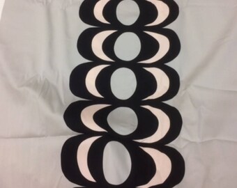 May include: A white fabric with a black and white geometric pattern. The pattern is a series of overlapping circles and ovals.