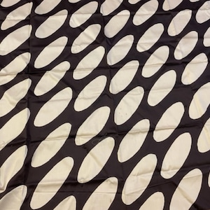 May include: Black fabric with a white oval pattern. The ovals are arranged in a diagonal pattern.