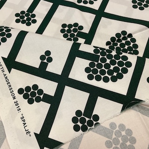 May include: White fabric with a repeating pattern of black squares and circles. The circles are arranged in clusters to form the shape of a tree. The fabric has the text "JOMI - INLAND CARINA SETH-ANDERSSON 2015: "SPALJÉ"