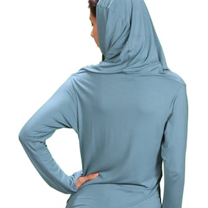 May include: A light blue hooded long-sleeve shirt with a relaxed fit. The shirt is made of a soft, comfortable fabric.