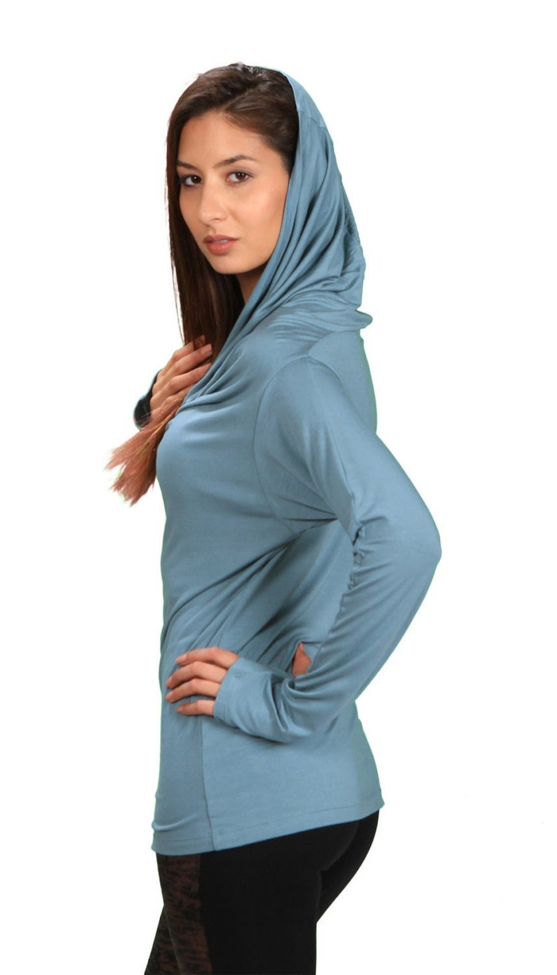 May include: A light blue long-sleeved shirt with a cowl neck and a hood. The shirt is made of a soft, stretchy fabric.