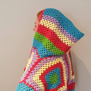 Puede incluir: Una colorida capucha de ganchillo con un patrón de granny squares en tonos de azul, verde, amarillo, rosa y rojo.