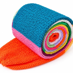 May include: A multi-colored knit scarf rolled into a cylinder, featuring vibrant horizontal stripes in shades of teal, pink, orange, yellow, green, purple, and white. The fabric has a consistent, textured garter stitch pattern throughout the entire piece.