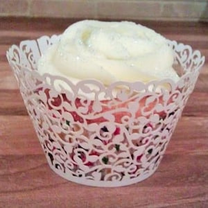 May include: White cupcake with white icing and a delicate white lace cupcake wrapper. The icing has a subtle sparkle.