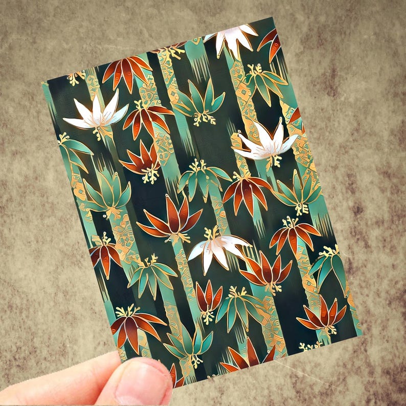 May include: A rectangular card featuring a repeating pattern of stylized leaves and floral elements. The design incorporates shades of green, orange, white, and gold against a dark background with vertical stripes. The card is held by a hand.