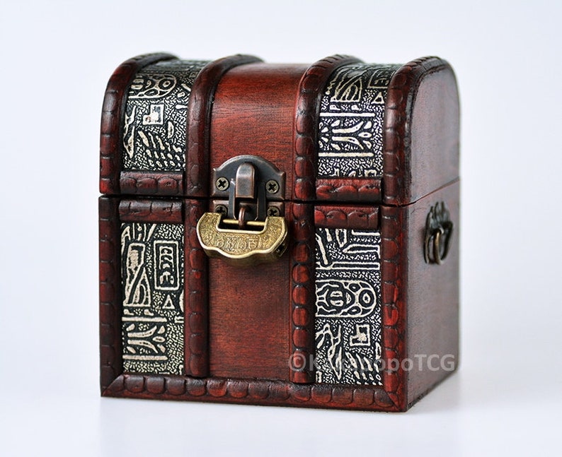 May include: A small wooden treasure chest with a brass lock and hinges. The chest is decorated with an intricate design of white and black patterns.