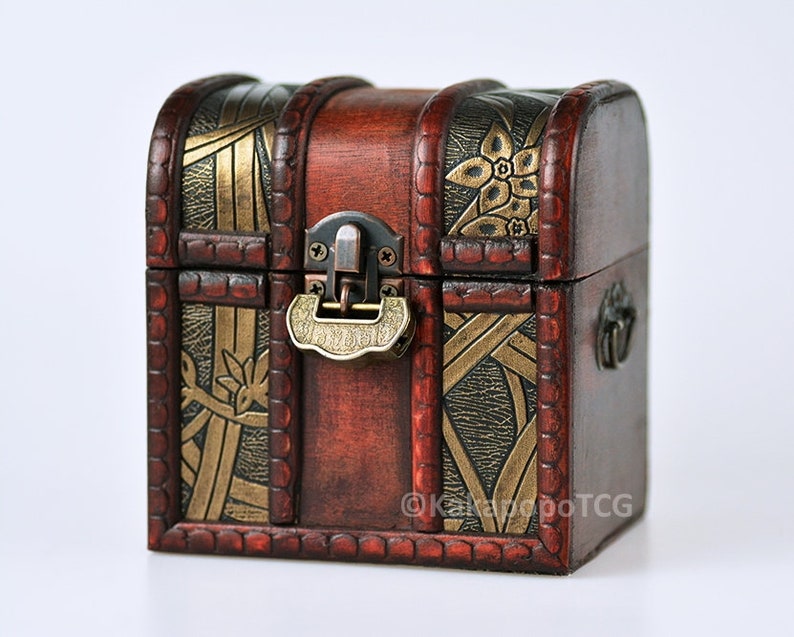 May include: A small wooden treasure chest with a hinged lid, ornate gold and black floral designs, and a brass latch.